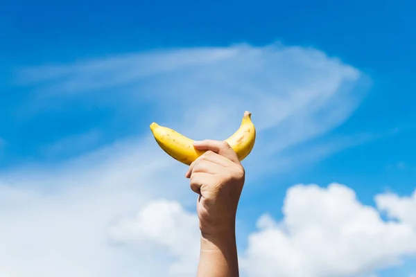 Jeden Żółty Banan Ludzkiej Dłoni Przeciwko Błękitnym Niebem — Zdjęcie stockowe