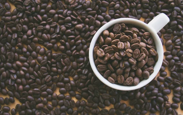 kahve çekirdekleri dolu beyaz kahve bardağı, Masa yüzeyinde tohumlar 