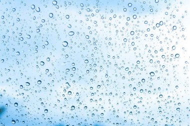 Mavi gökyüzü arka plan üzerinde cam su damlaları 