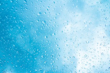 Mavi gökyüzü arka plan üzerinde cam su damlaları 