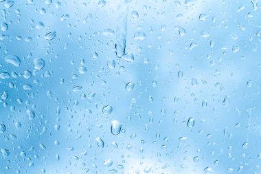 Mavi gökyüzü arka plan üzerinde cam su damlaları 