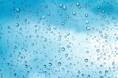 Mavi gökyüzü arka plan üzerinde cam su damlaları 