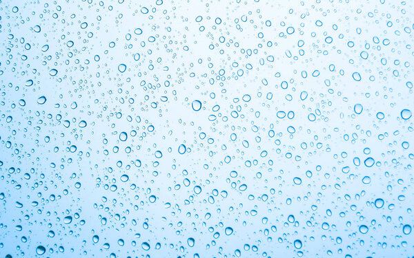 Water drops on glass on blue sky background 