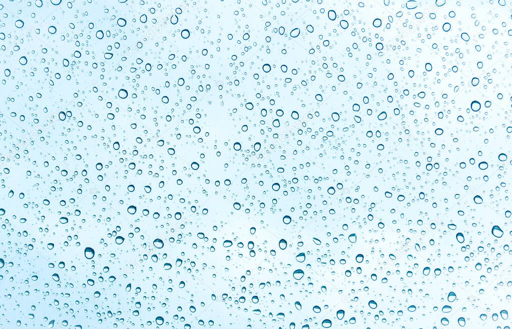 Water drops on glass on blue sky background 