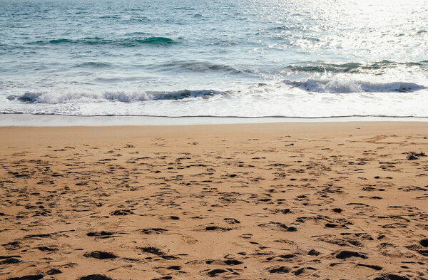 Ocean wave on sandy beach with foot print on sand background