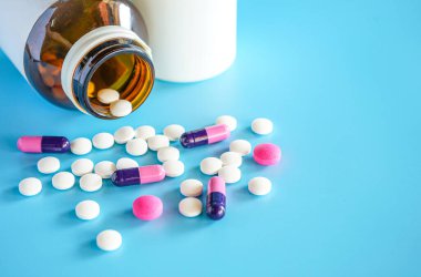 Mavi arka planda teblet haplı hap şişesi seçici odaklı.