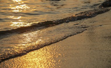 Gün batımlı ya da gündoğumu plajlı deniz dalgaları ve kum arka planlı