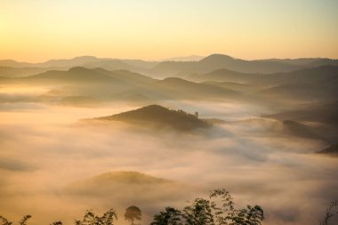 Gün doğumunda sisli dağları yakalıyor
