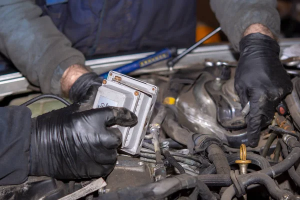 Car mechanic repairs diesel engine. Old and dirty car engine with car mechanics hands. Car repairing concept in the garage workshop.