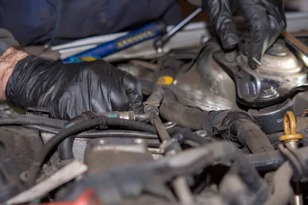 Car mechanic repairs diesel engine. Old and dirty car engine with car mechanics hands. Car repairing concept in the garage workshop.