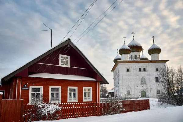 Деревенская хижина зимой на фоне храма — стоковое фото