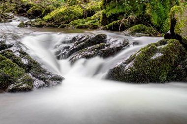 Exmoor Ulusal Parkı 'ndaki Watersmeet' te kayaların üzerinden akan bir şelaleye uzun süre maruz kalmak