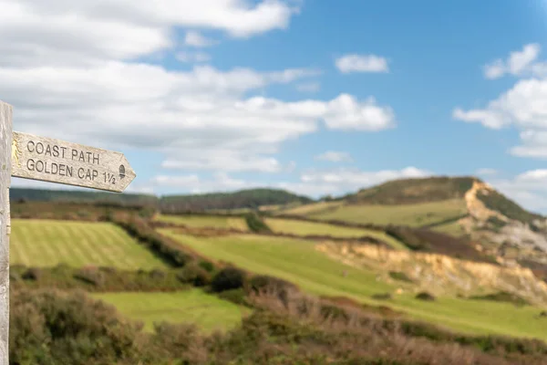 stock image Close up of a wooden signpost pointing to Golden Cap mountain with Golden Cap mountain in the background