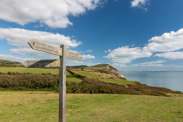 Close up of a sign post pointing towards Golden Cap mountain with Golden Cap mountain in the background