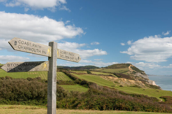 Close up of a sign post pointing towards Golden Cap mountain with Golden Cap mountain in the background