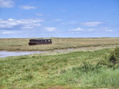 Brancaster Marsh 'taki ev teknesi, Kuzey Norfolk sahilinde Burnham Deepdale yakınlarında..