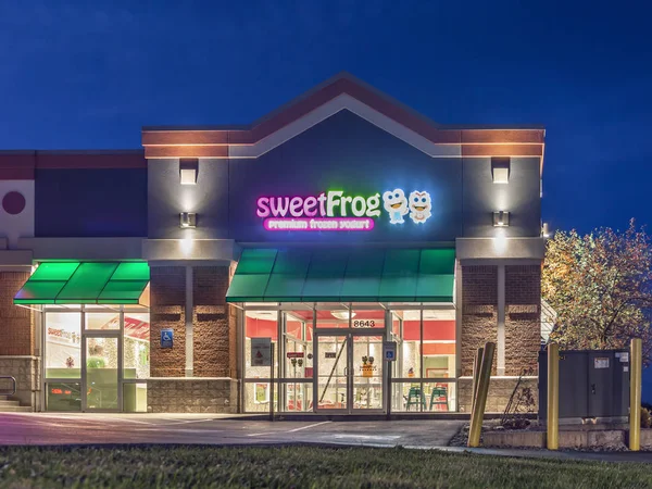 Nueva Hartford, Nueva York - 29 de octubre de 2019: Vista nocturna de la tienda de la cadena de helados de yogur congelado Sweet Frog con signo y logotipo . — Foto de Stock
