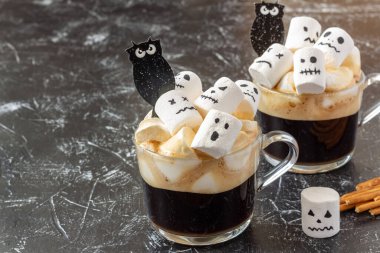 Kahve fincanındaki şekerlemelerden ürkünç yüzler (canavar). Karanlık arka planda Cadılar Bayramı yemeği. Şenlik konsepti. Boşluğu kopyala