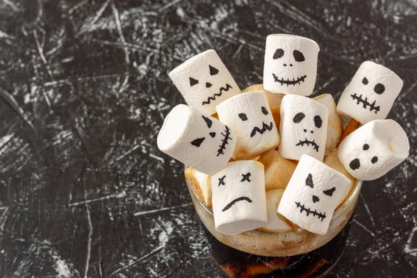 Creepy faces (monster) from marshmallows in cup of coffee for Halloween. Festive concept. Copy space. Top view