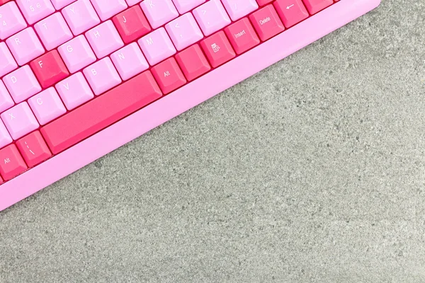 Small pink slim keyboard for computeron a gray background. Copy space