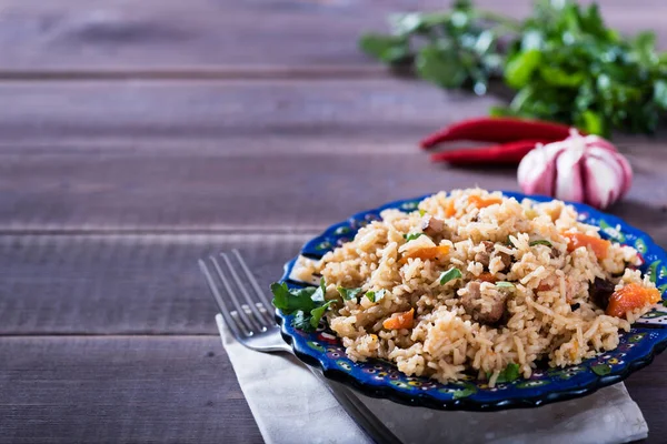 Pilaf - geleneksel doğu yemeği pirinç, sebze ve etle yapılır. Asya yemekleri. Doğu mutfağı kavramı, ahşap bir masa üzerinde.