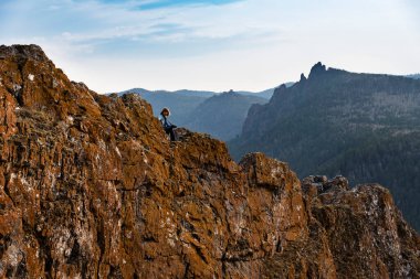 Bir kadın dağın tepesinde oturur ve bir dağın güzelliğine ve güzel manzaraya hayran kalır. Kadın güzel yerlere seyahat ediyor..