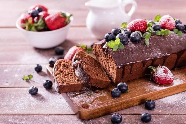 Taze lezzetli ev yapımı çikolatalı pasta ve ahşap bir masada yaz meyveleri..