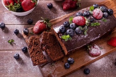 Taze lezzetli ev yapımı çikolatalı pasta ve ahşap bir masada yaz meyveleri..