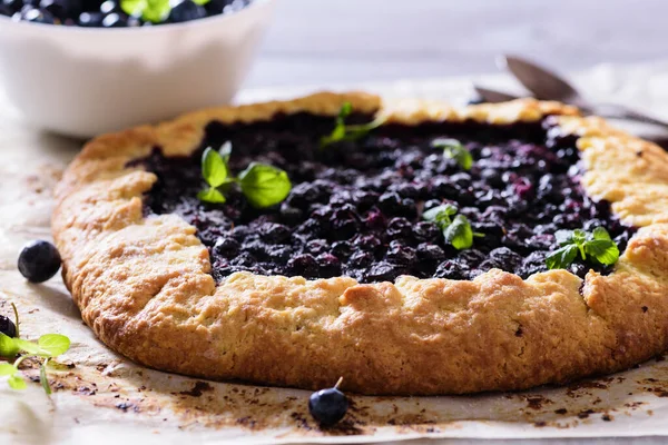 Ev yapımı çıtır yaban mersinli turta veya galette ve nane. Yaz, parlak, lezzetli turtalar çiçeklerle çerçevelenmiş ve böğürtlenli otlar