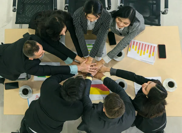 Business team People with diverse nationalities are chatting and meeting together on the table in the meeting room. A group of businesspeople showing unity And friendship by shaking hands. top view