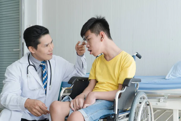 Asian Volunteer Doctors Caring and Helping Rehabilitation of Disabled Boys Stay at the hospital. The boy is crippled, Asian people can\'t help themselves. Must sit in a wheelchair all the time