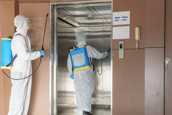 穿着防护服和戴口罩的专业男工在受污染地区喷洒消毒剂 控制病毒和细菌 — 图库照片