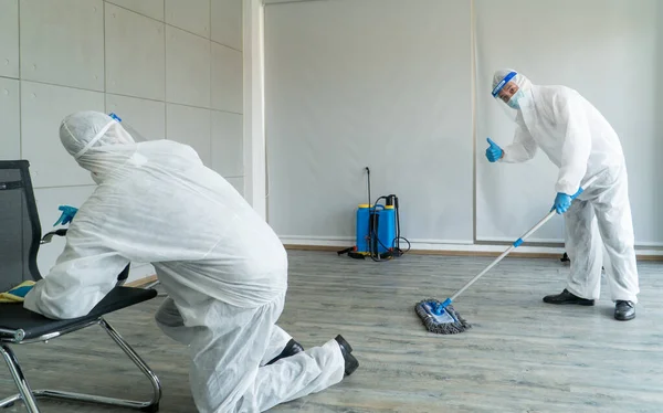 Professional  male worker In protective clothing and masks are spraying disinfectants, cleaning, controlling virus and bacteria in the contaminated area After the spread of coronavirus or COVID-19