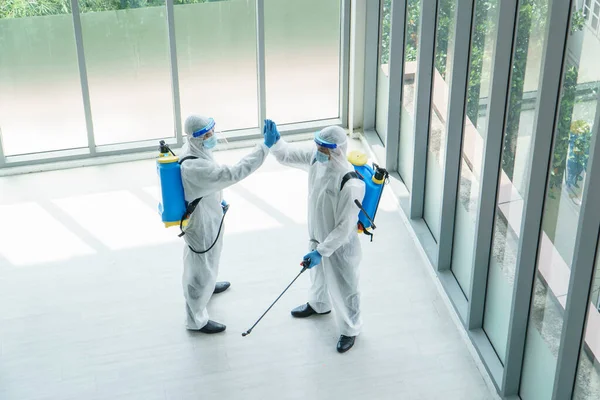 穿着防护服和戴口罩的专业男工在受污染地区喷洒消毒剂 控制病毒和细菌 — 图库照片