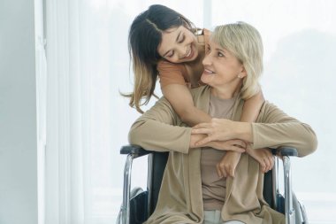 Mutlu bir gülümseme Kafkasyalı son sınıf öğrencisi, Asyalı torununa sarılıyor. Aile kavramını birleştirin. Cilt, sevgi, zaman bakımı, büyükanne, torun, anne ve kız, üvey anne ya da üvey kız evlatlık.