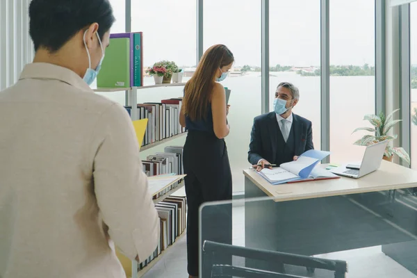 Business people wear a protective mask to work together in the company office. social distancing is the new normal. The concept of preventing the spread of coronavirus or COVID-19