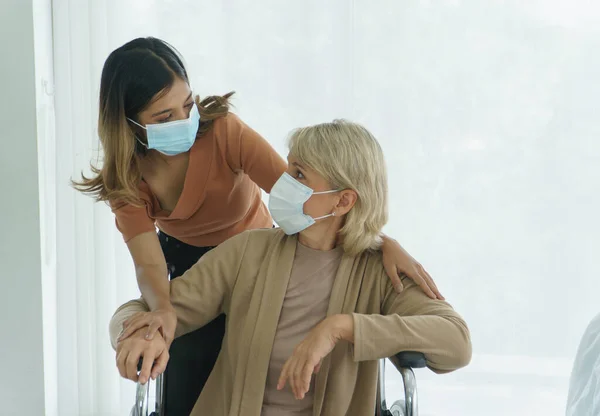 Koruyucu maske takan mutlu anne ve kız evde eğleniyor. Çeşit çeşit bir aile. Sevgi paylaşım zamanı kavramı Büyükanne, anne, kız, torun ve evlatlık için bakım