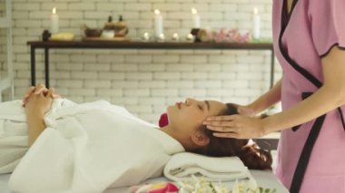 Güzeller güzeli Asyalı kadınları spa salonunda yatakta yatırmak. Tayland masajı yapan genç bir kadın. Masözün eli kadının alnına masaj yapıyor. Fikirler kadınlar için masaj ve spa