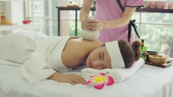 放松躺在温泉沙龙床上的美丽的亚洲女人 年轻女人在做泰式按摩按手用草药按压按摩妇女的肩背 为妇女提供按摩和温泉服务 — 图库视频影像