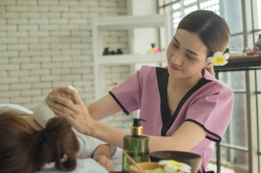 Genç Asyalı kadın spa salonunda mutlu bir şekilde gülümsüyor.