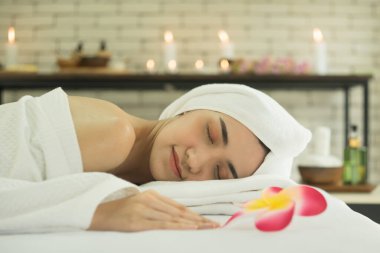 Güzel bir Asyalı kadın spa salonunda uzanıyor ve yatakta dinleniyor. Doğal otlar ve kadınlar için kaplıca geleneksel masaj konsepti.