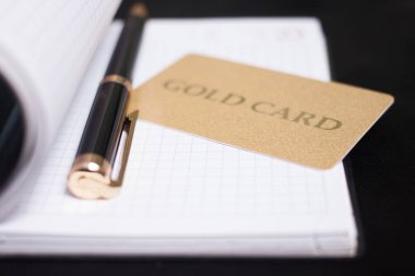 Bir kredi kartı yakınındaki bir açık defter üzerinde siyah kalem