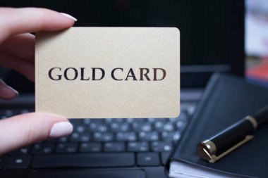 Altın kredi kartı elinde. Siyah arka plan üstünde Laptop