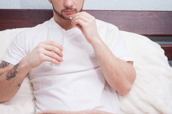 Handsome young man taking pill