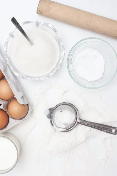 Baking ingredients: flour, eggs, sugar, butter, milk and spices on gray marble background