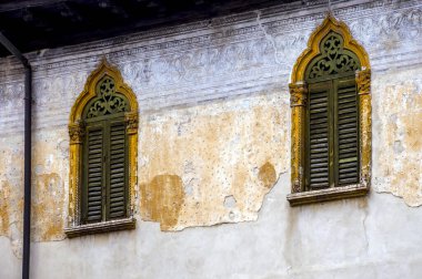 İki yeşil pencereli eski sarı bir cephenin parçası, Verona, İtalya