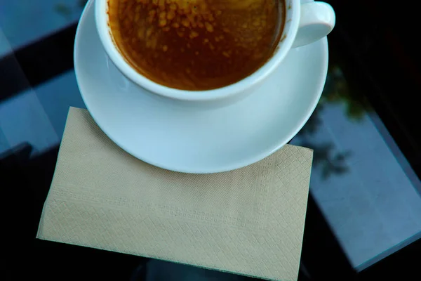 質感のためのスペースとコーヒーの白いカップの下の茶色いティッシュペーパーのトップビュー — ストック写真