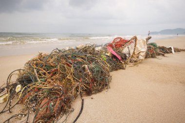 Washed-up fishing nets on the beach / Garbage in the sea having negative impacts on the ecology system clipart