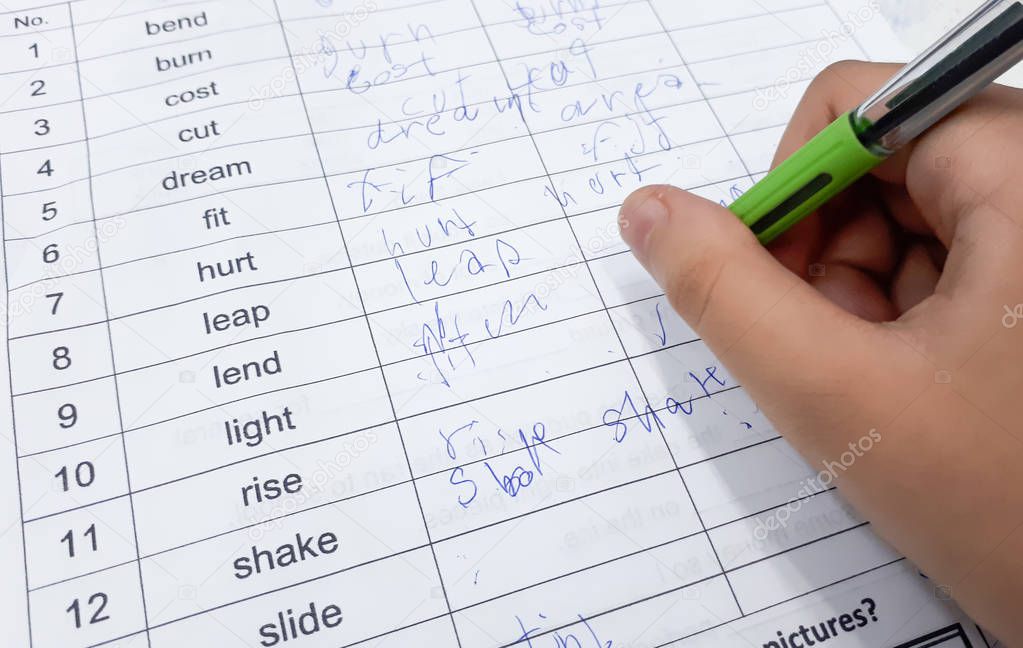 Student with a bad handwriting writing irregular verbs
