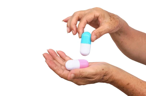 白い背景にアイロルトされた2つの大きなカプセル薬を持つ老女性の手 薬物過剰摂取の概念 — ストック写真